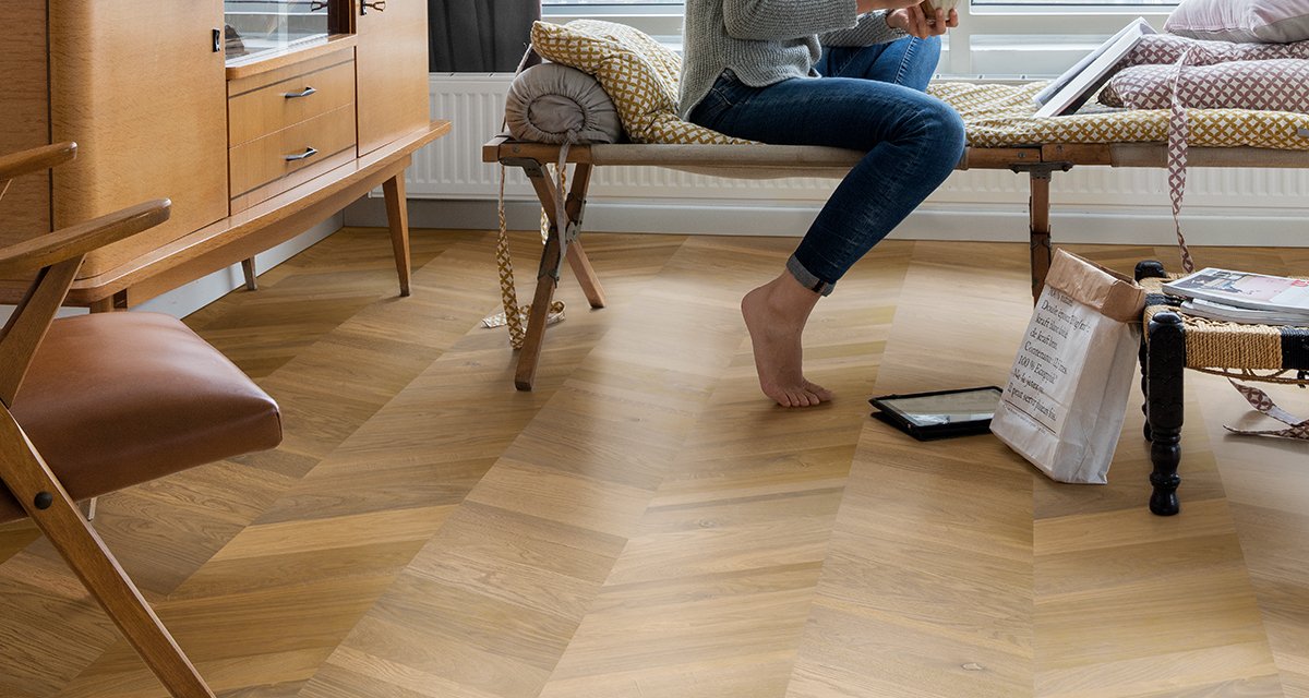 Modern living room featuring a seamless chevron laminate floor pattern.